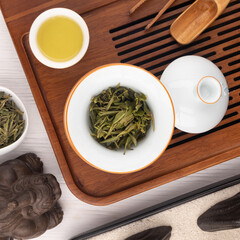 Green tea in a bowl and teapot on a wooden tea tray. Chinese tea ceremony.