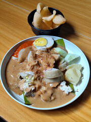 Gado Gado, traditional Indonesian vegetable salad with peanut sauce, chili sauce, lontong, tofu, cucumber, potatoes, and egg.