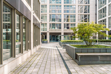 Modern office buildings with glass facades surrounding a courtyard with greenery and seating areas