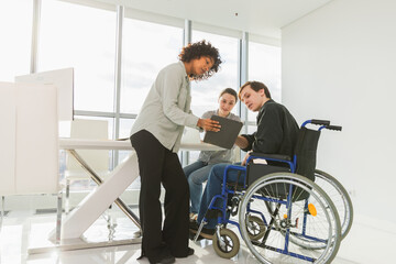 Teamwork brainstorm. Diverse multiracial colleagues man in chair for people with disability working together. Group of people sitting in creative office discussing business. Young professional team