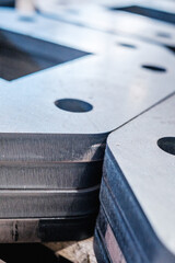 Close-up of stacked metal plates with precision cut holes, industrial steel manufacturing detail showing engineering and fabrication process