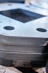 Precision-cut metal plates with circular and square holes, close-up of industrial steel components from plasma or laser cutting process