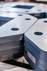 Stacked laser-cut steel plates with precision holes, close-up of industrial metal parts prepared for mechanical fabrication or structural assembly