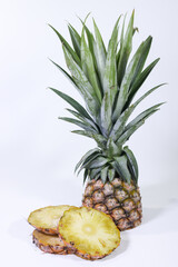 Whole Pineapple and Sliced Pieces on a White Background