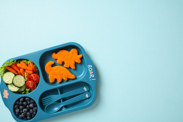 Playful dinosaur-themed kids lunch tray with healthy snacks and nuggets.
