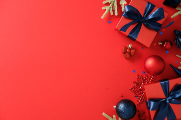 Christmas flat lay with red gift boxes, blue ribbons, ornaments, and glitter on red background. Perfect for Christmas promotions, greeting cards, and seasonal ads