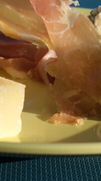 Cheese prosciutto fork Charcuterie board, cheese platter, a hand pricks a cube of gouda cheese with a wooden toothpick