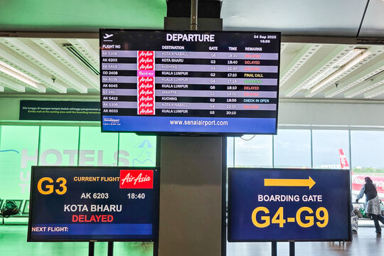 Air departure information board in Senai airport boarding gate with many Air Asia flights delayed