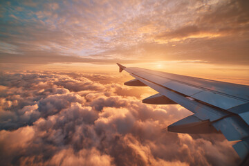 Airplane wing soaring above a sea of golden clouds at sunset, dramatic sky with warm light and soft textures conveying travel, freedom and expansive aerial perspective.