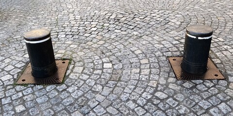 Retractable security bollards on cobblestone pavement. Two retractable bollards installed on cobblestone pavement used for traffic control and pedestrian safety.   
