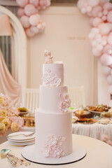 Elegant white wedding cake adorned with pink flowers at a reception