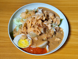 Gado Gado, traditional Indonesian vegetable salad with peanut sauce, chili sauce, lontong, tofu, cucumber, potatoes, and egg.
