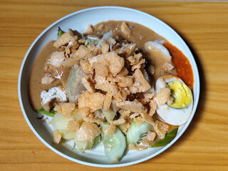 Gado Gado, traditional Indonesian vegetable salad with peanut sauce, chili sauce, lontong, tofu, cucumber, potatoes, and egg.