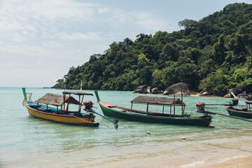 Obraz premium Colorful longtail boats floating on calm turquoise water near Surin tropical islands in Thailand, offering a serene view of the shore of the Morgan Village
