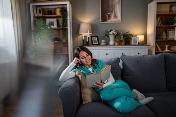 Naklejka premium Healthcare worker relaxing while reading book on sofa