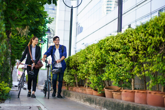 People walking bicycle on city street. Modern urban lifestyle.