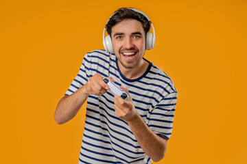 Excited Gamer Man Playing Online Video Game On Console With Gamepad On Yellow