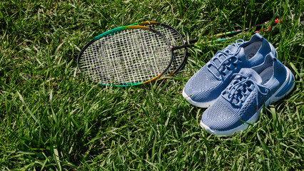 composition with racket and tennis shoes on green grass background. Concept of active recreation,...