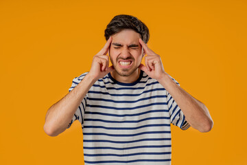 20s aged man having headache, touching temples, Suffering on yellow background.