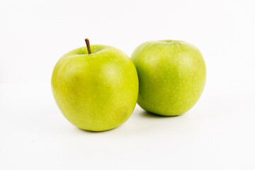 Pair of crisp green apples displays healthy fruit against a bright plain background.