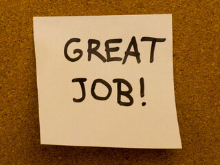 Sticky note with great job message on corkboard background