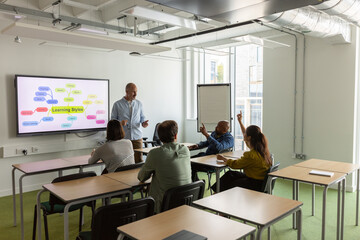 Adult students putting their hand up to ask a question in class