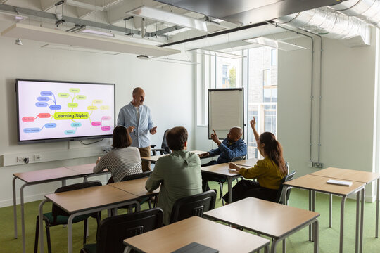 Adult students putting their hand up to ask a question in class