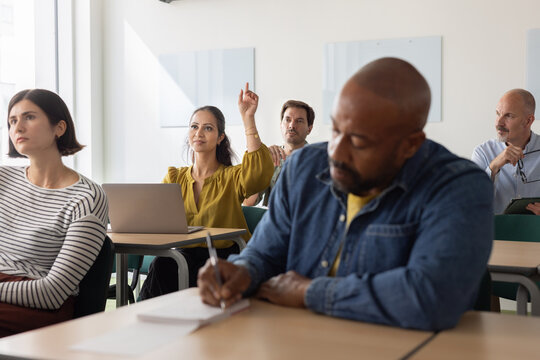 Engaged adult student raising her hand in class