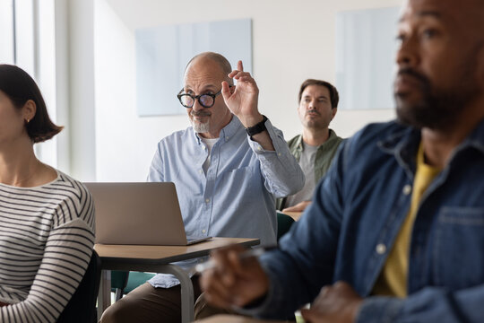 Engaged adult student raising his hand in class