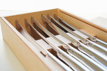 Closeup of Steak knives in a wooden box on white background