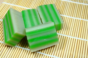 Traditional Indonesian layered rice cakes, known as Kue Lapis, featuring a striking pattern of green and white stripes on a bamboo mat