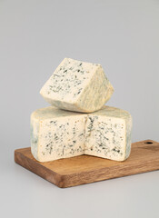 Gorgonzola on wooden board isolated on grey background.