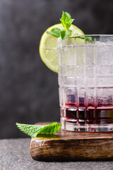 Cocktail with ice in a glass on a wooden cutting board