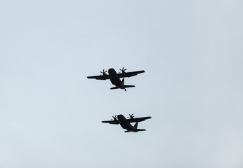 Two synchronized flying military transport aircraft from which paratroopers are just starting to jump