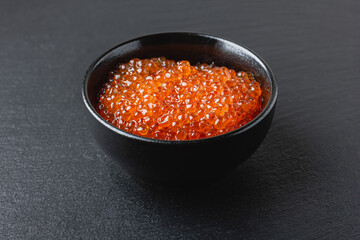 Salmon red caviar in a black bowl