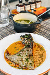 Grilled fish dish with orange sauce and green onion.