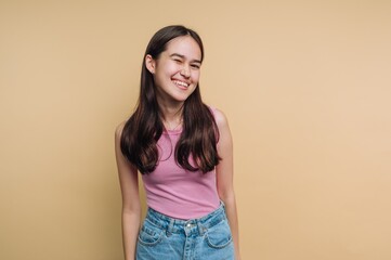 Obraz premium Smiling young woman in casual outfit against beige background.