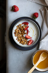 Healthy breakfast with yogurt, granola, and fresh strawberries. Top view, vertical orientation.