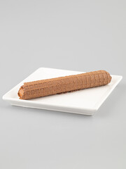 Chocolate wafer rolls on a white plate on a grey background