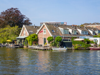 Fototapeta premium Oude Rijn (Old Rhine) and Dutch houses by canal in Leiden with boats and greenery, summer European travel