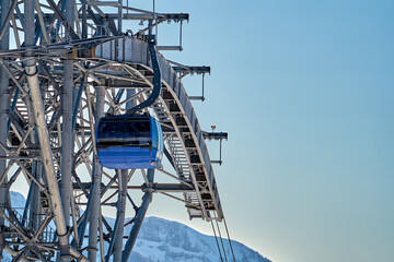 Gondola, cable car and ski lift with mountain, tree, blue sky on a sunny day at resort Krasnaya Polyana.