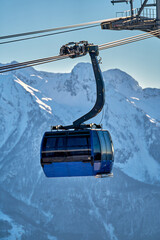 Gondola, cable car and ski lift with mountain, tree, blue sky on a sunny day at resort Krasnaya Polyana.