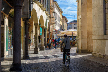 Old narrow street with arcade, bicycle and tables of restaurant in Padua (Padova), Veneto, Italy. Cozy cityscape of Padua