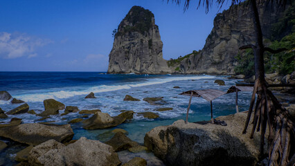 Rocky beaches with clear blue sea water and towering coral cliffs, combined with clear skies.