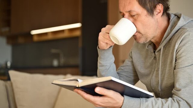 Lifelong learning concept, man reading book at home in living room in the morning, 4K