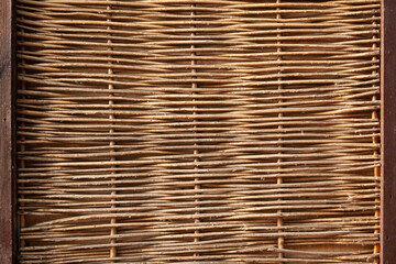 Fence made of woven branches shows rustic craftsmanship in outdoor setting
