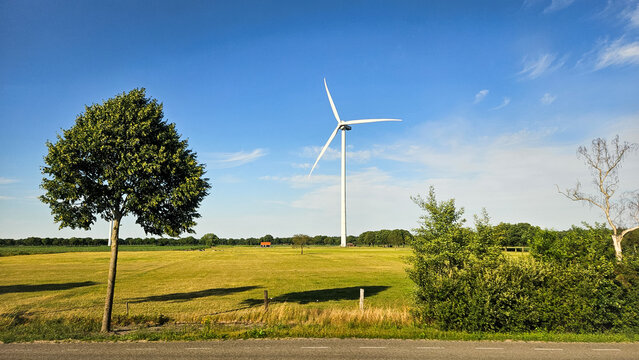 Panorama photo of white wind turbine in nature farming Dutch landscape.
