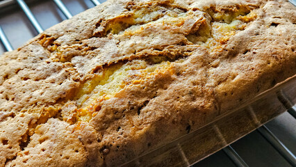 Fresh cake in baking tin on cooling rack, homemade baked snack treat out of the oven.