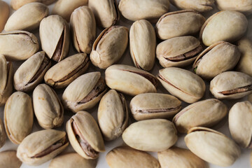 Fototapeta premium Pistachios with shell top view on a white background with shallow depth of field. Pistachio nuts, healthy, natural snack treat.