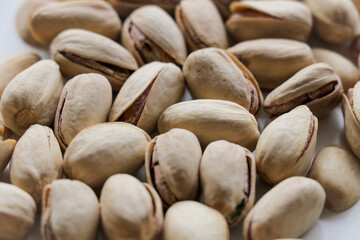 Close up pistachios with shell top view on a white background with shallow depth of field. Pistachio nuts, healthy, natural snack treat.